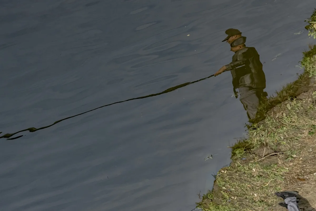 Fisherman and his reflection stretching across still water